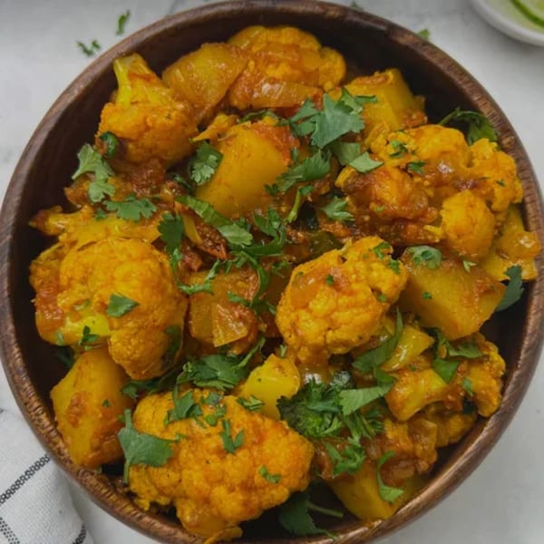 Indian Wok's Aloo Gobi, a vibrant yellow cauliflower and potato curry, garnished with fresh cilantro.